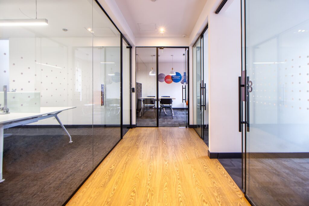 Best Office Space in Karachi for Startups and Small Teams Bright modern office hallway with glass walls leading to a conference room.